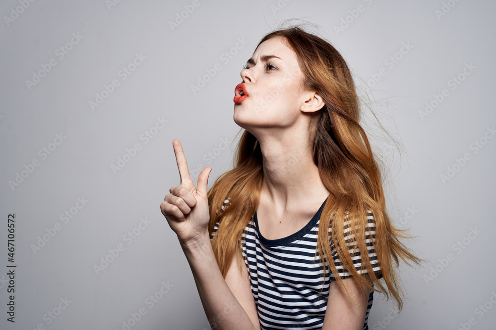 pretty woman in a striped t-shirt gesture with his hands light background pretty woman in a striped t-shirt gesture with his hands light background