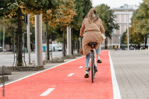 traffic, city transport and people concept - woman riding bicycle along red bike lane or two way road on street © Syda Productions