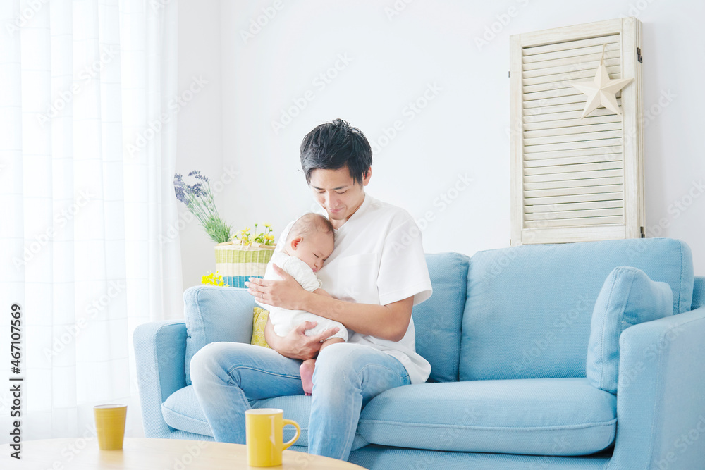 部屋で赤ちゃんを抱っこする父親 部屋で赤ちゃんを抱っこする父親