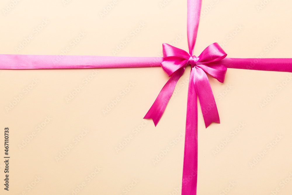 Top view of purple ribbon rolled and pink bow isolated on colored background. Flat lay with copy space Top view of purple ribbon rolled and pink bow isolated on colored background. Flat lay with copy space