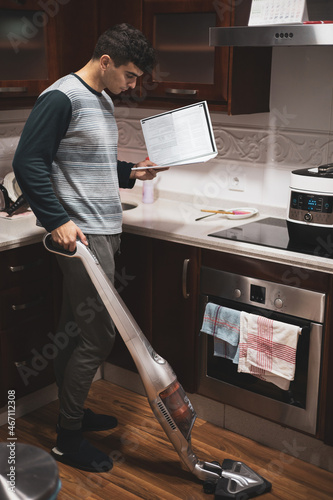 
an adult man vacuuming while studying and taking care of food. photo