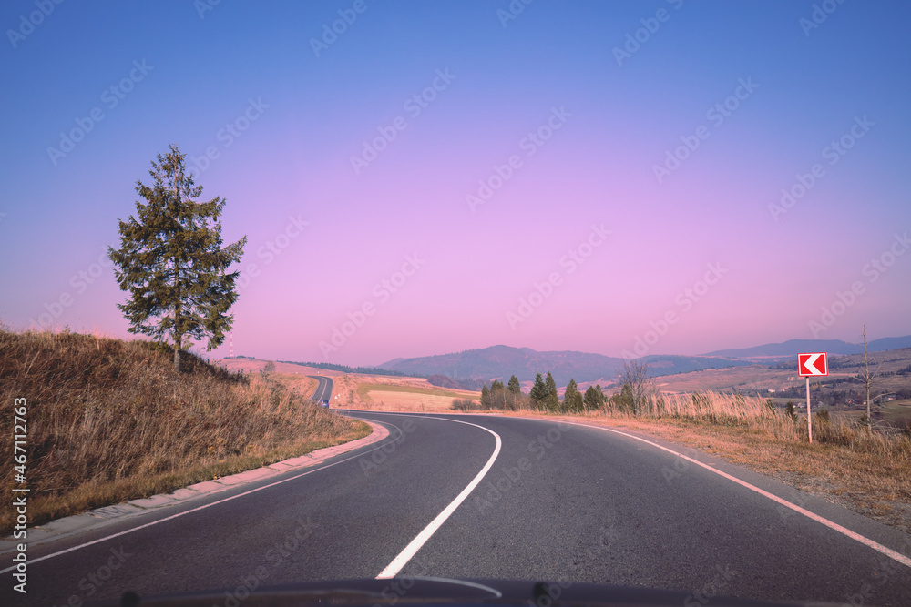 Fototapeta premium View of the mountain winding road from windscreen during sunrise