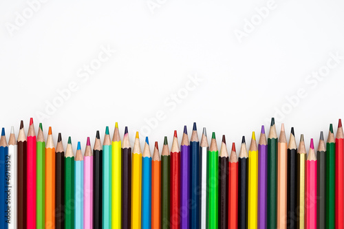 Back to school or creativity concept. Wavy frame made of colored crayons against white background. Table top view, flat lay, copy space.