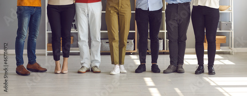 Banner with team of young and senior people who work together standing in company office. Group of friends or colleagues standing in row. Cropped shot of human legs in classic and casual denim pants