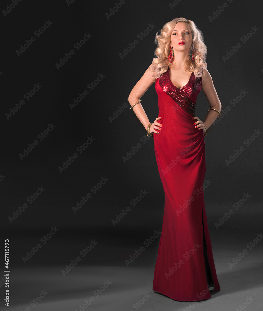 woman in red dress studio portrait - sensual beautiful blonde model posing stands in a dark copy paste place background. Attractive sexy girl with long curly hair. Blurred details woman in red dress studio portrait - sensual beautiful blonde model posing stands in a dark copy paste place background. Attractive sexy girl with long curly hair. Blurred details