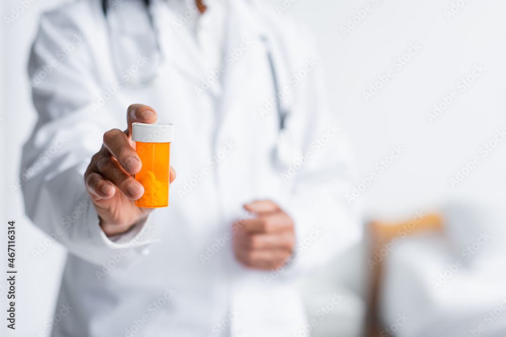 Cropped view of blurred doctor holding pills in hospital Cropped view of blurred doctor holding pills in hospital