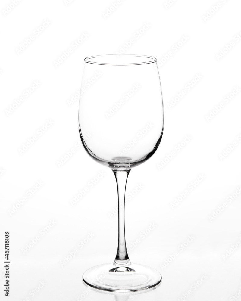 Empty wine glass on a white background. The stem of the glass is reflected in a white background.