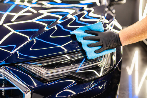 A man cleaning car with cloth, car detailing (or valeting) concept. Selective focus.