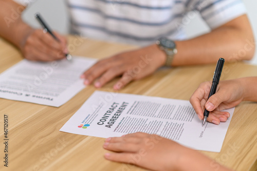Male and female employees sign a contract together.