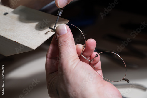Optical technician fixing glasses. Close-up of male hands with screwdriver and goggles frame.