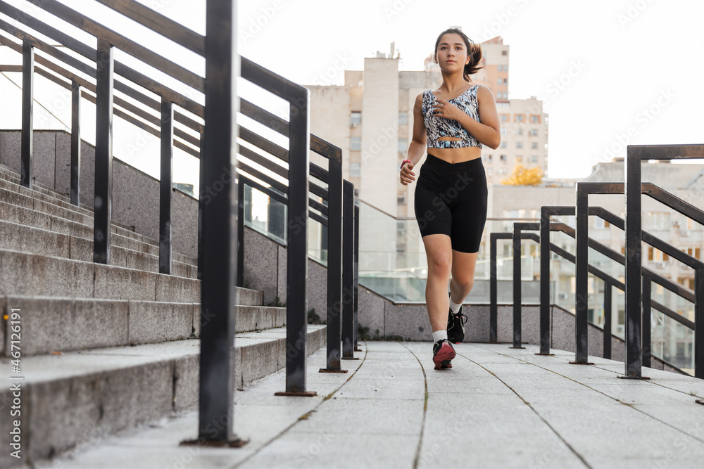 Obraz premium Teenage girl doing jogging near stadium outdoors of the city background