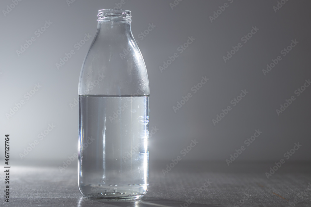 Glass water bottle on a gray background. copy space Glass water bottle on a gray background. copy space