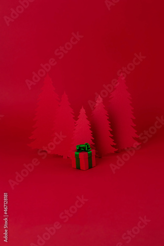 Christmas creative concept. Red Christmas tree of paper with red gift on the red background. Holiday concept.