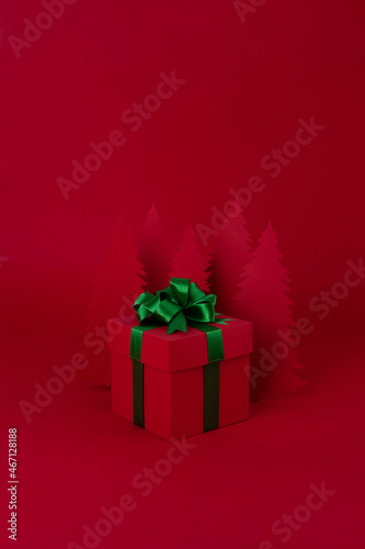 Christmas creative concept. Red Christmas tree of paper with red gift on the red background. Holiday concept.