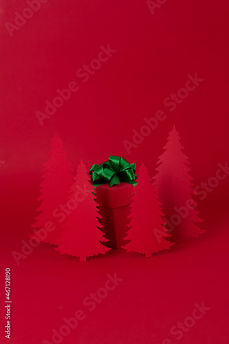 Christmas creative concept. Red Christmas tree of paper with red gift on the red background. Holiday concept.