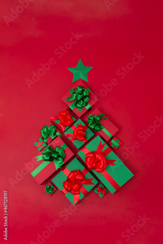 Christmas creative concept. Christmas tree made of different small and big gift boxes on the red background. Holiday concept.