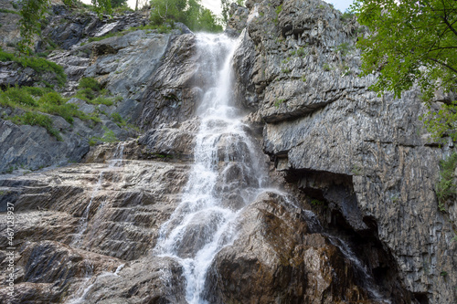 high waterfall on a small river among rocks and green trees