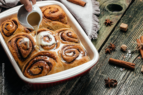 Freshly baked sweet cinnamon buns rolls with vanilla cream. Food recipe background. Close up photo