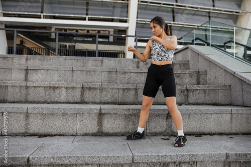 Teenage girl doing sports warm-up and wrestling exercises on the street against the city background photo