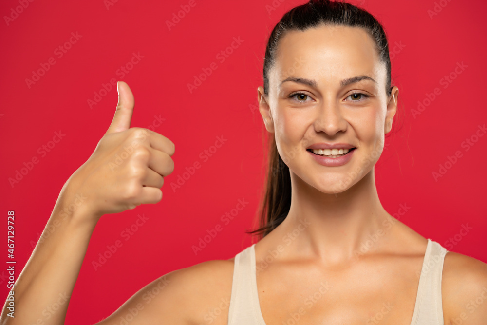 Portrait of beautiful smiling woman with tied hair showing thumb up Portrait of beautiful smiling woman with tied hair showing thumb up