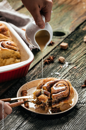 Cinnamon sinnabon bun, with vanilla creame on wooden background. vertical image. top view. place for text photo