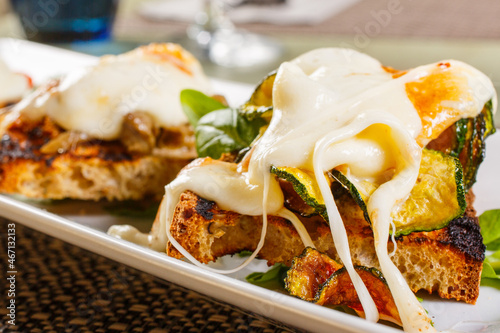 Bruschetta di pane tostato con provola filante, zucchine e basilico fresco photo