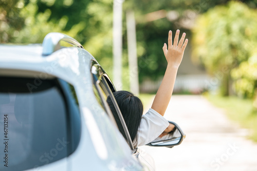 woman waving her hand from the car window.
