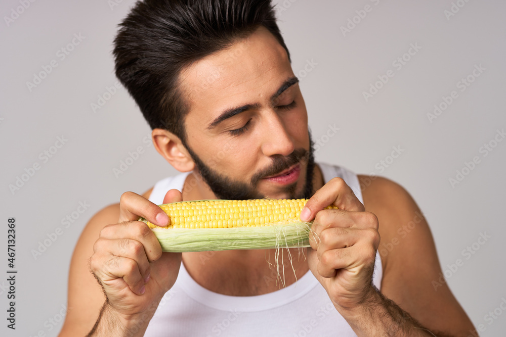 Cheerful man eating corn diet isolated background Cheerful man eating corn diet isolated background