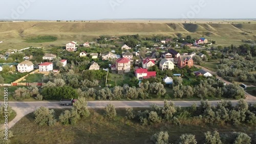 Aerial view of a road in a small town. A dump truck with a red cab moves along the road.
