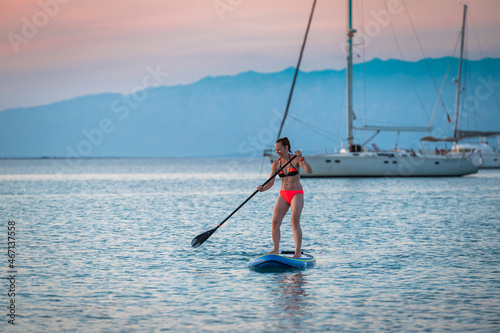 Woman riding SUP stand up paddle on vacation.