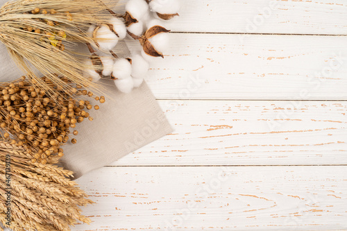 Flower composition. A border of dried flowers, wheat, cotton, ears, linen on beige linen towel.