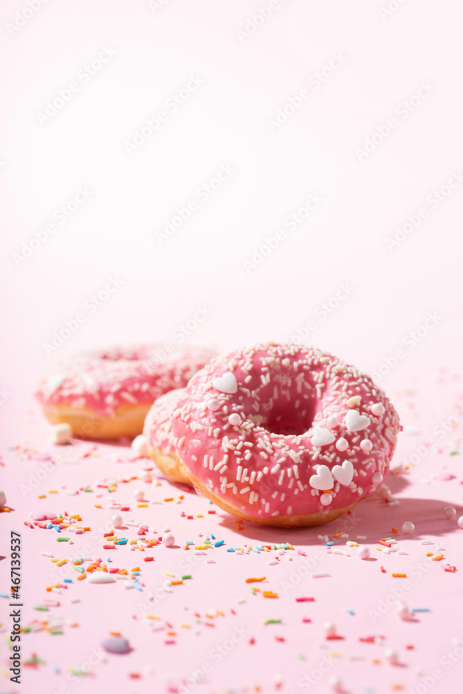 Donuts with pink icing and sugar sprinkle on pink background Donuts with pink icing and sugar sprinkle on pink background