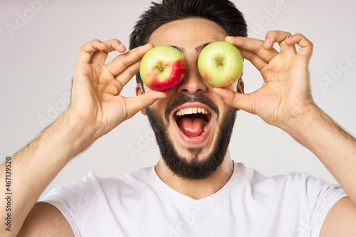 Cheerful man with apples in his hands in a white t-shirt fruits