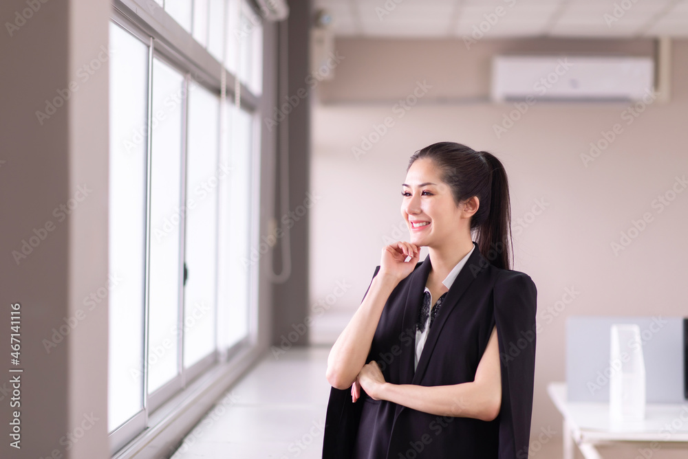 Beautiful business asian woman standing and looking on window in the office Beautiful business asian woman standing and looking on window in the office