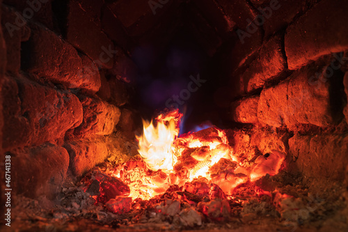 Hot coals inside an old rustic brick oven. There are yellow and blue flames. Background. Texture.