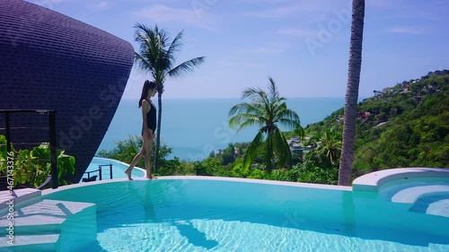 Sexy Woman In Swimming Suit In Luxurious Villa Walking to Sea View Infinity Pool