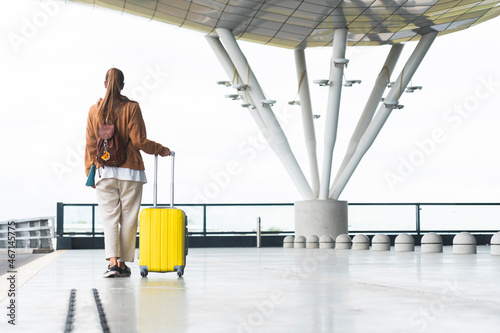 Woman holding wheeled luggage while walking at airport photo