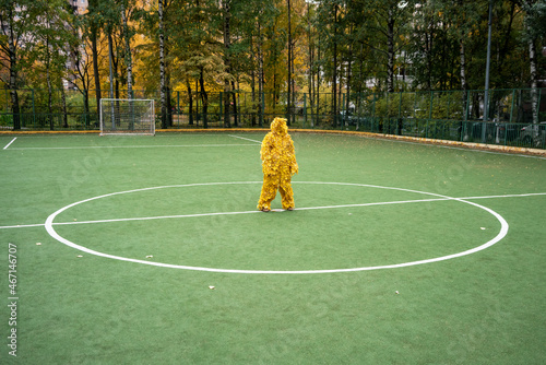 Woman with yellow leaf costume standing at sports court