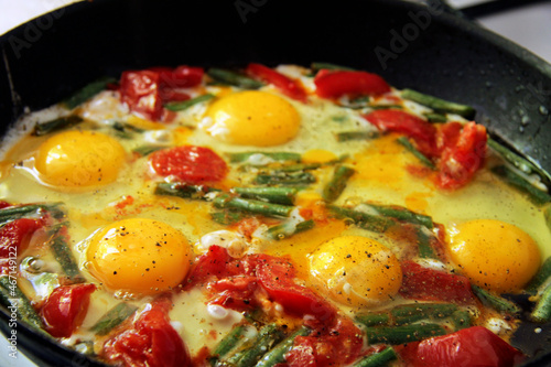 Morning roasted whole eggs on the black plate and with tomato and green beans
