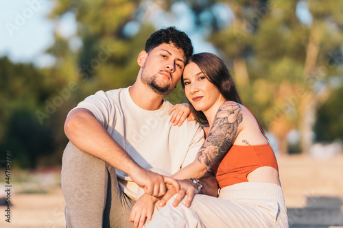 Couple facing the camera while sitting together on a park during sunset