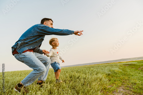 Young white father pointing finger aside while standing with his son