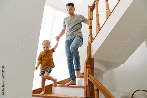Young white father going down stairs with his son