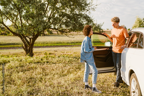 Young multiracial couple talking and standing by car during trip © Drobot Dean