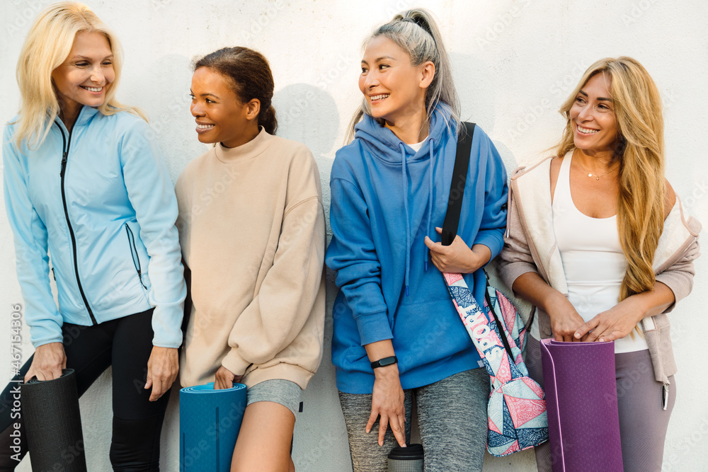 Multiracial women talking and laughing after yoga practice Multiracial women talking and laughing after yoga practice