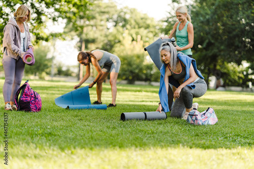 Multiracial women unrolling their mats during yoga practice in park