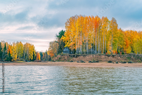 Panoramic view of the bright colorful trees along the bank of the Chusovaya River Russia Perm Krai. Autumn colored trees and blue sky, reflected in the calm and shiny water.