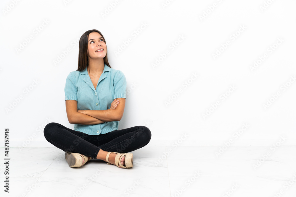 Teenager girl sitting on the floor looking up while smiling Teenager girl sitting on the floor looking up while smiling