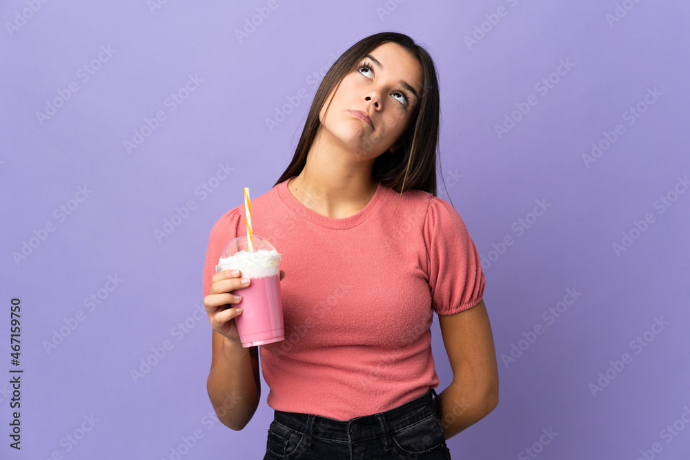Teenager girl holding a strawberry milkshake and looking up Teenager girl holding a strawberry milkshake and looking up