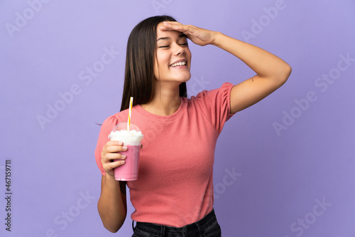 Teenager girl holding a strawberry milkshake smiling a lot