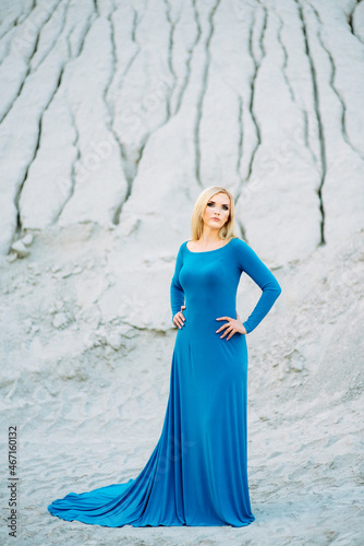 blonde girl in a blue dress with blue eyes in a granite quarry